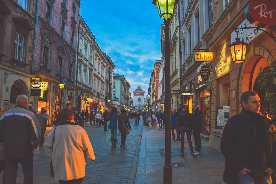 Bustling European street with historic buildings and evening shoppers under the vibrant dusk sky.