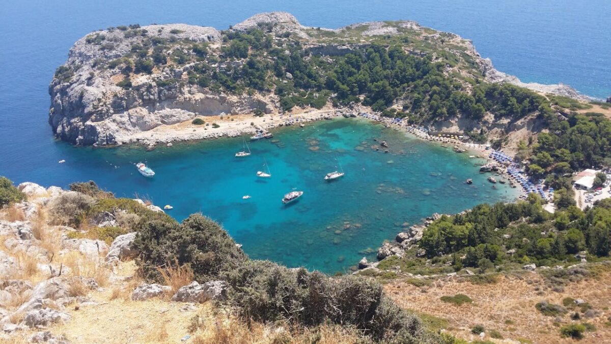 A stunning aerial view of a turquoise lagoon surrounded by rocky cliffs and lush greenery, ideal for travel enthusiasts.