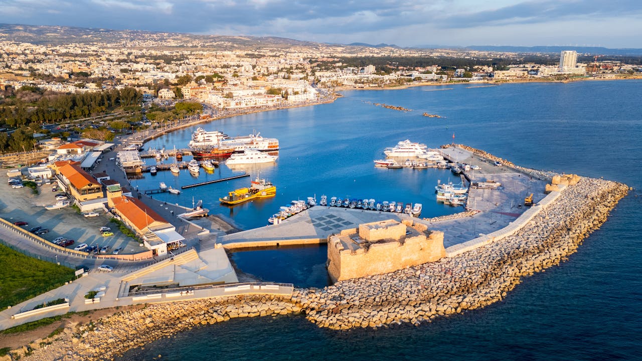 Stunning aerial view of Paphos Harbor and medieval fort in Cyprus, showcasing yachts and coast.