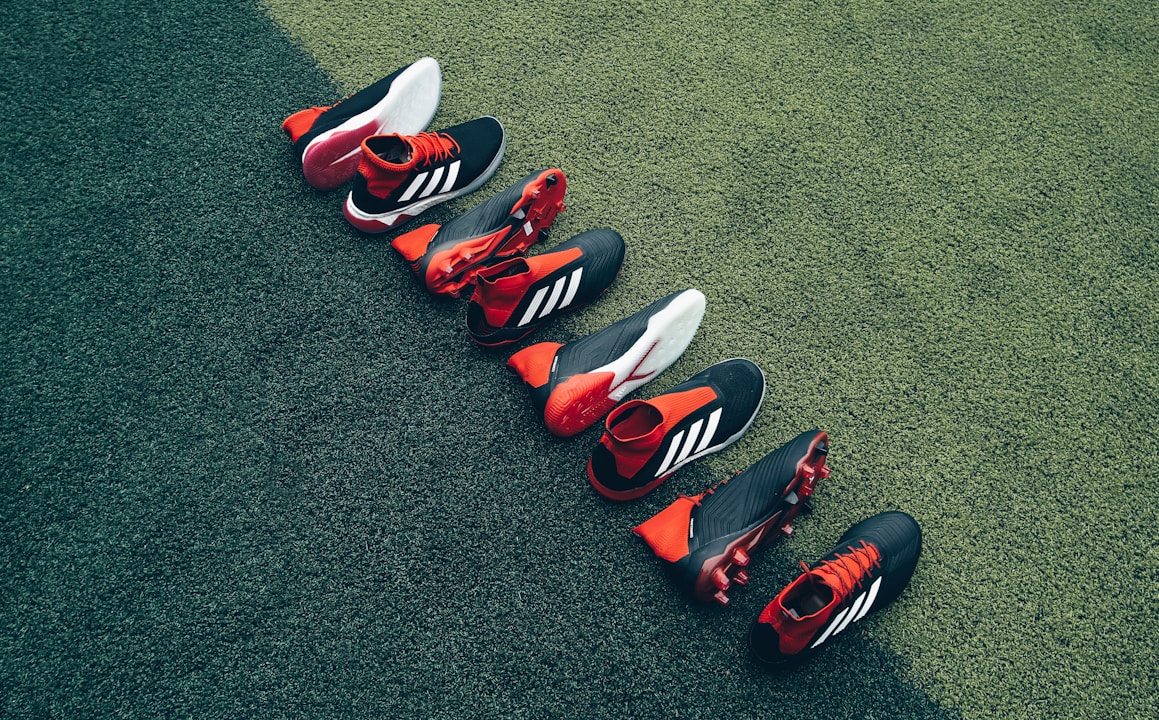 four pairs of black-and-orange shoes laid on green grass